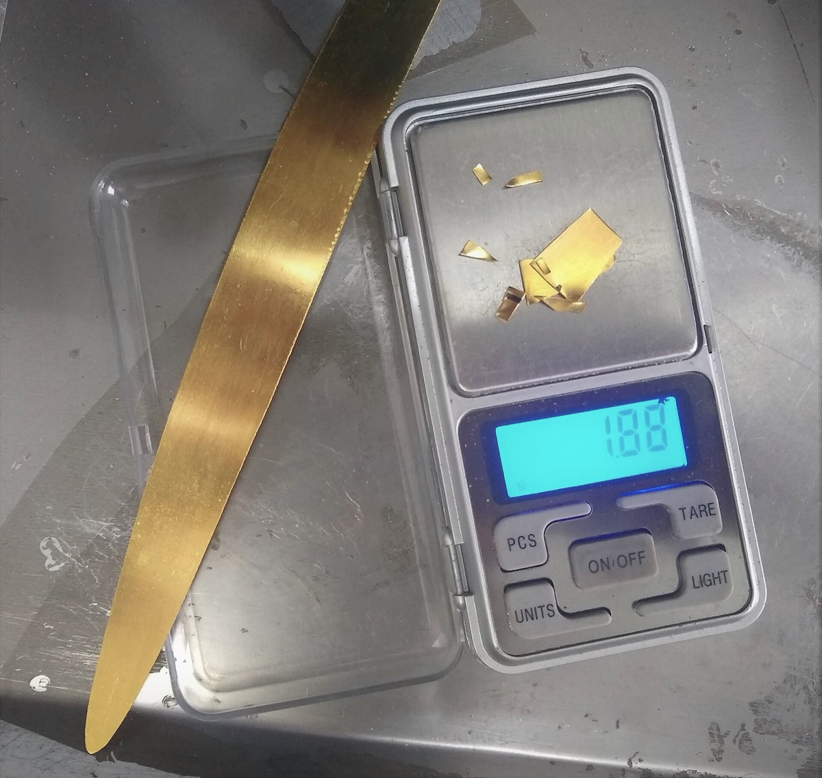 Aranydarabkák egy digitális zsebmérlegen, a kijelzőn 1,88 gramm